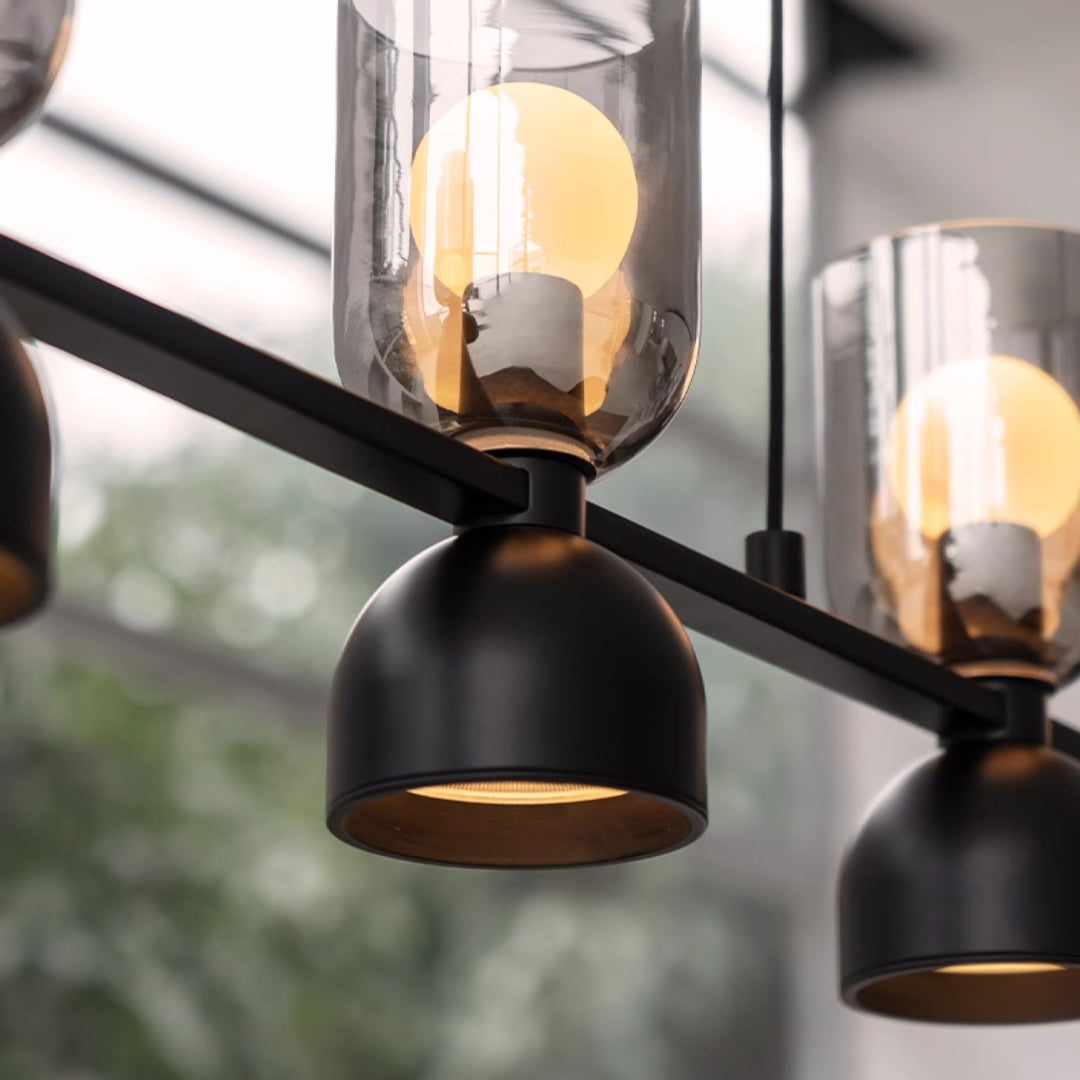Close-up of industrial glass pendant chandelier showing metal holder and glowing bulb detail.