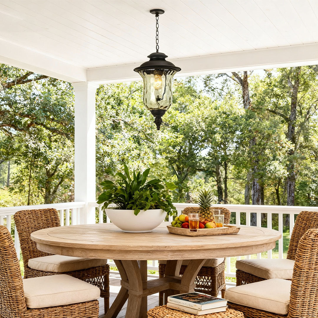 Industrial metal pendant light brightening covered patio dining area with wicker furniture at dusk