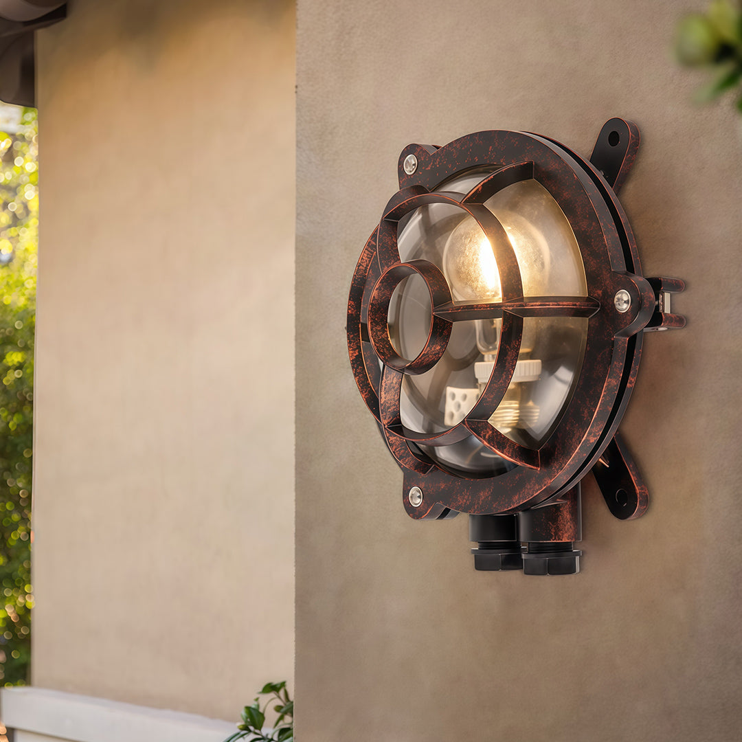 Industrial outdoor sconce on beige exterior wall with round porthole design creating warm evening glow
