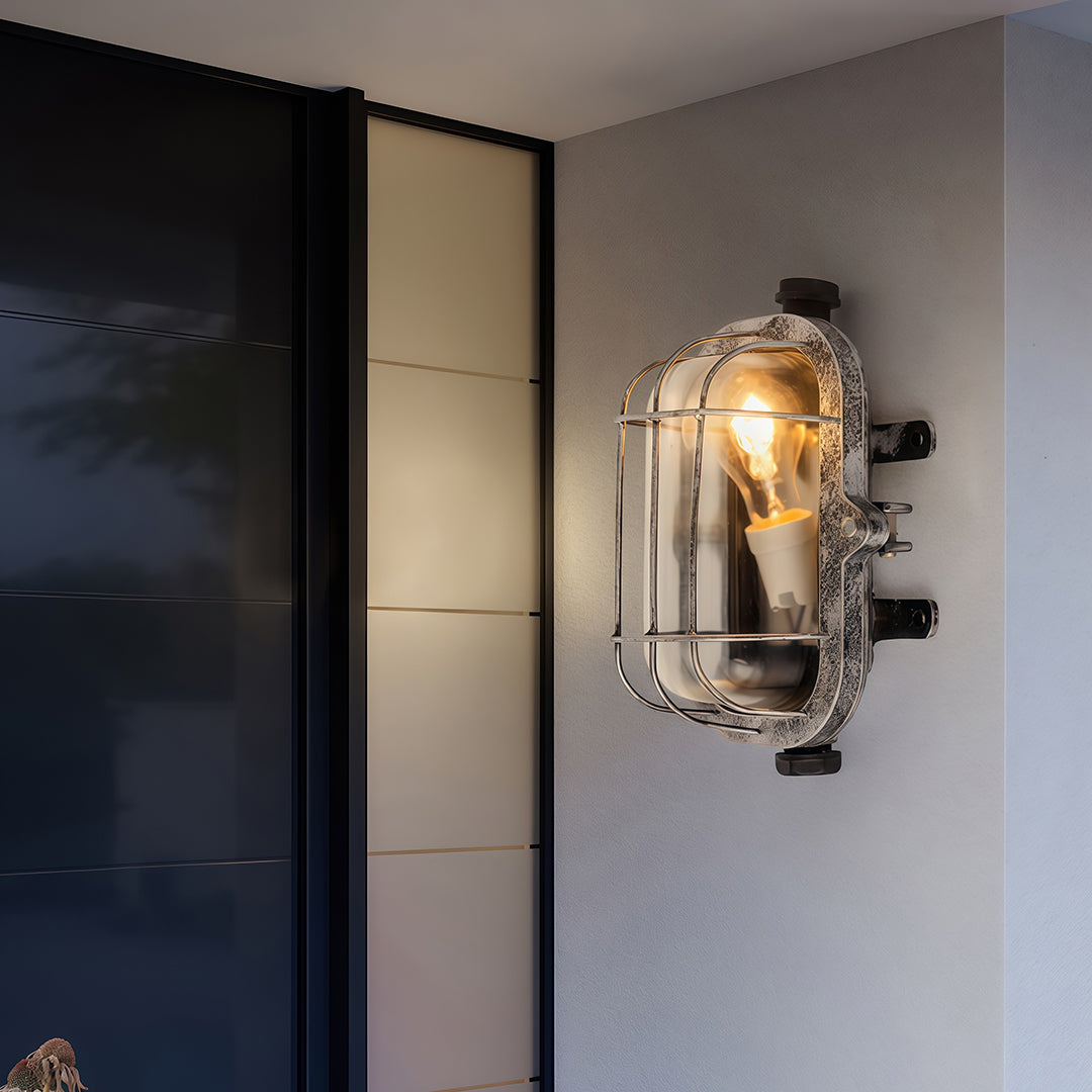Industrial outdoor sconce mounted on modern entrance wall providing warm ambient lighting at entryway