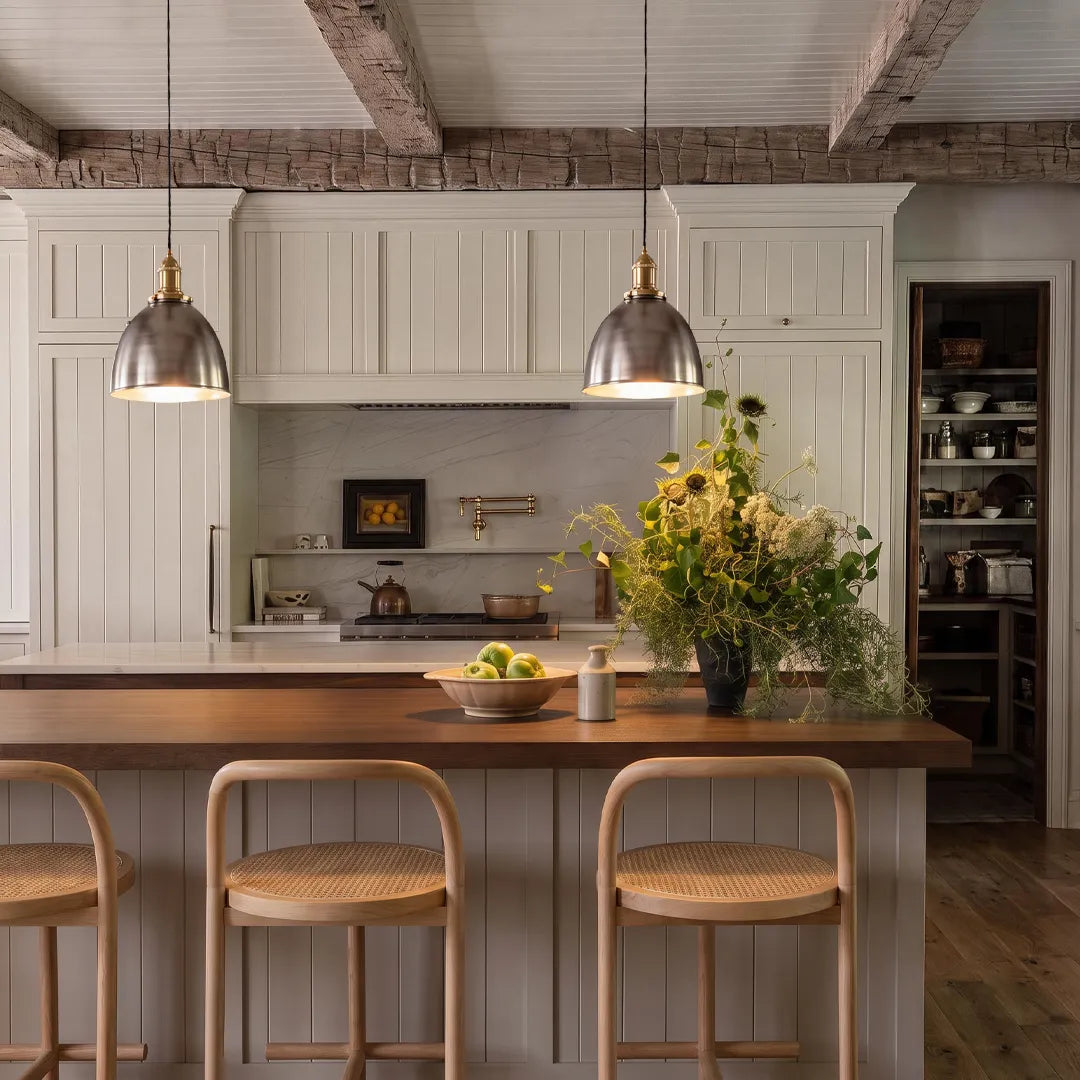 Industrial pendant lighting fixtures hanging above a kitchen island in a bright white farmhouse kitchen.