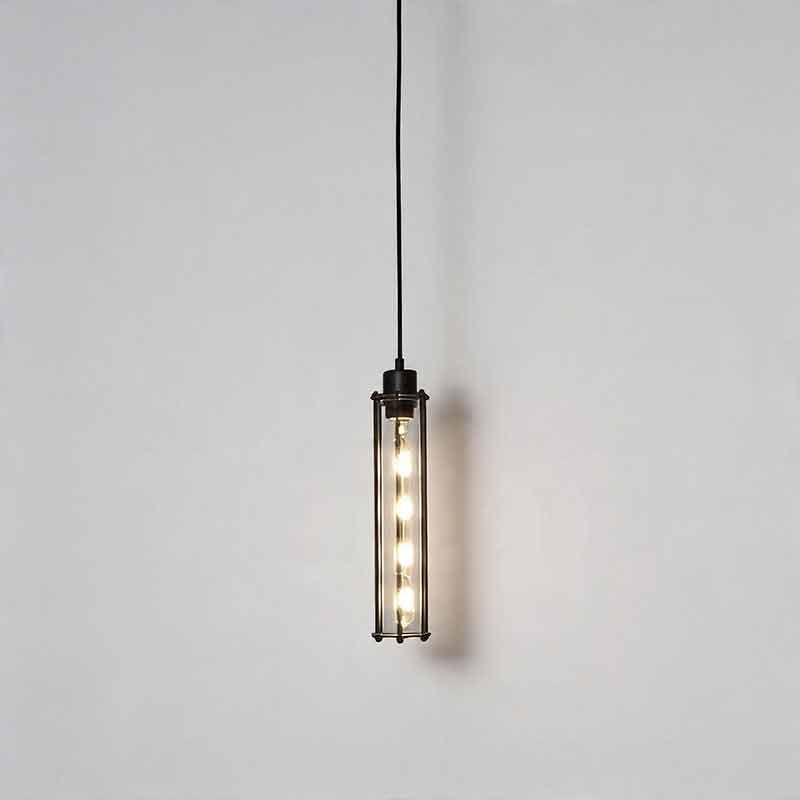 Industrial style pendant light fixtures glowing warmly against a gray wall hanging on a cord ok