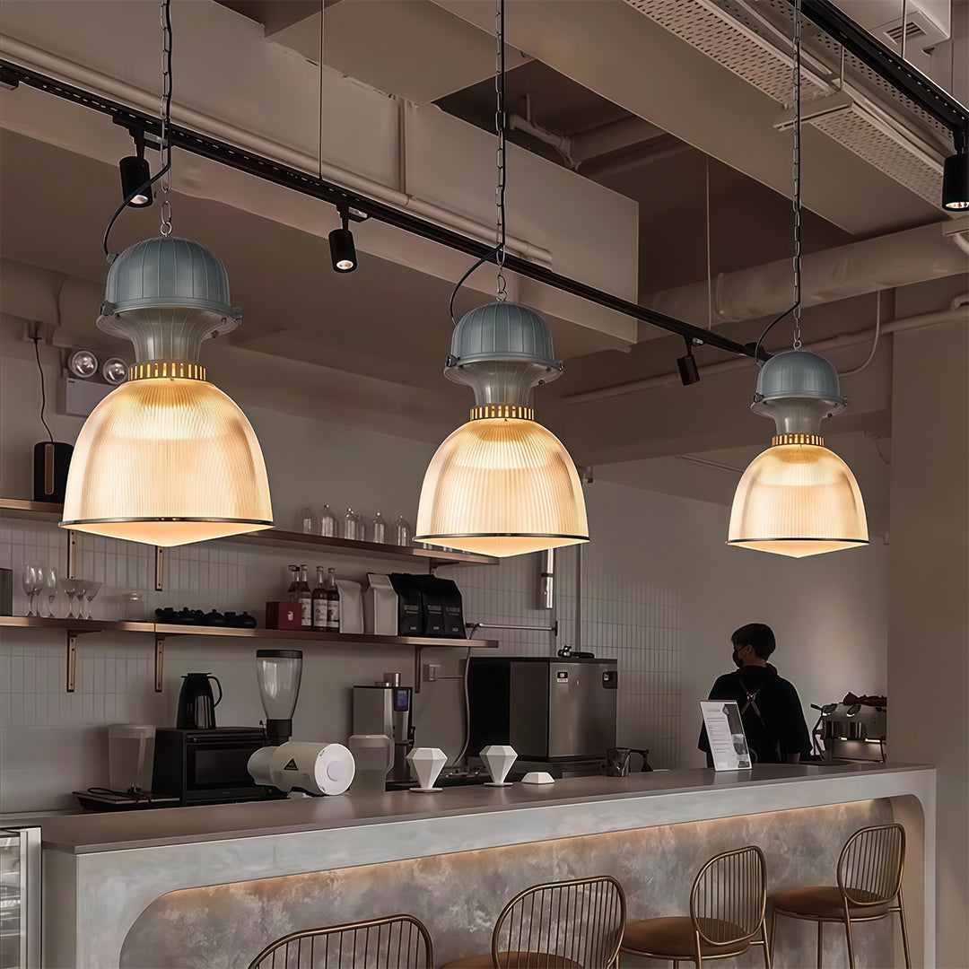 Row of industrial style pendant lighting over commercial kitchen counter with professional cooking space