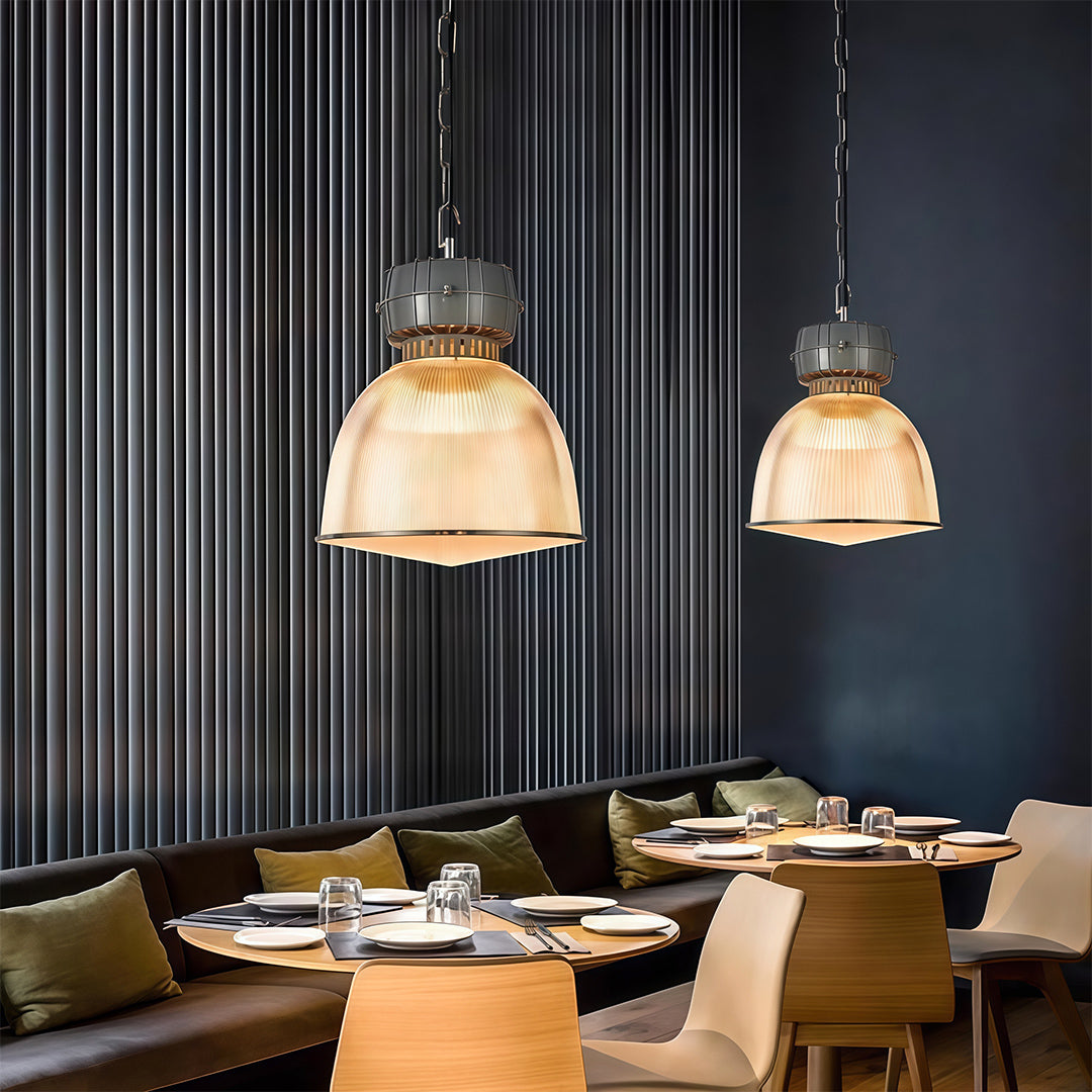 Pair of industrial style pendant lighting fixtures over dining table in contemporary dark interior setting