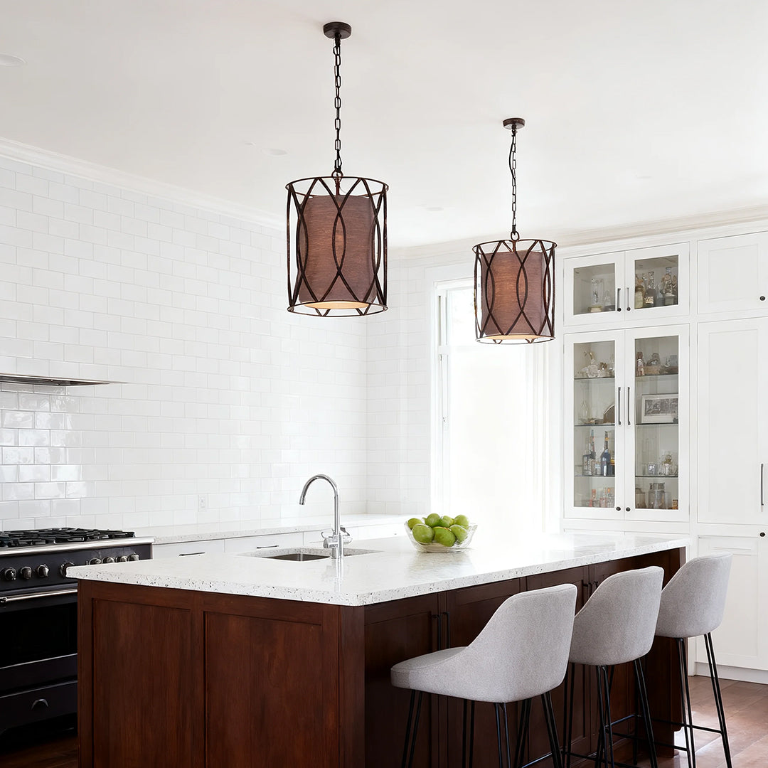 Two industrial-style small black pendant light fixtures illuminating a dark walnut kitchen island and bright white subway tile backsplash.