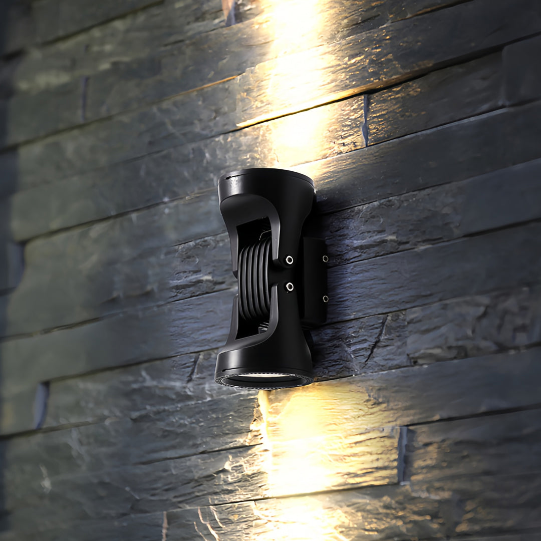 Industrial-style two light wall sconce mounted on a dark brick wall with warm lighting effect.