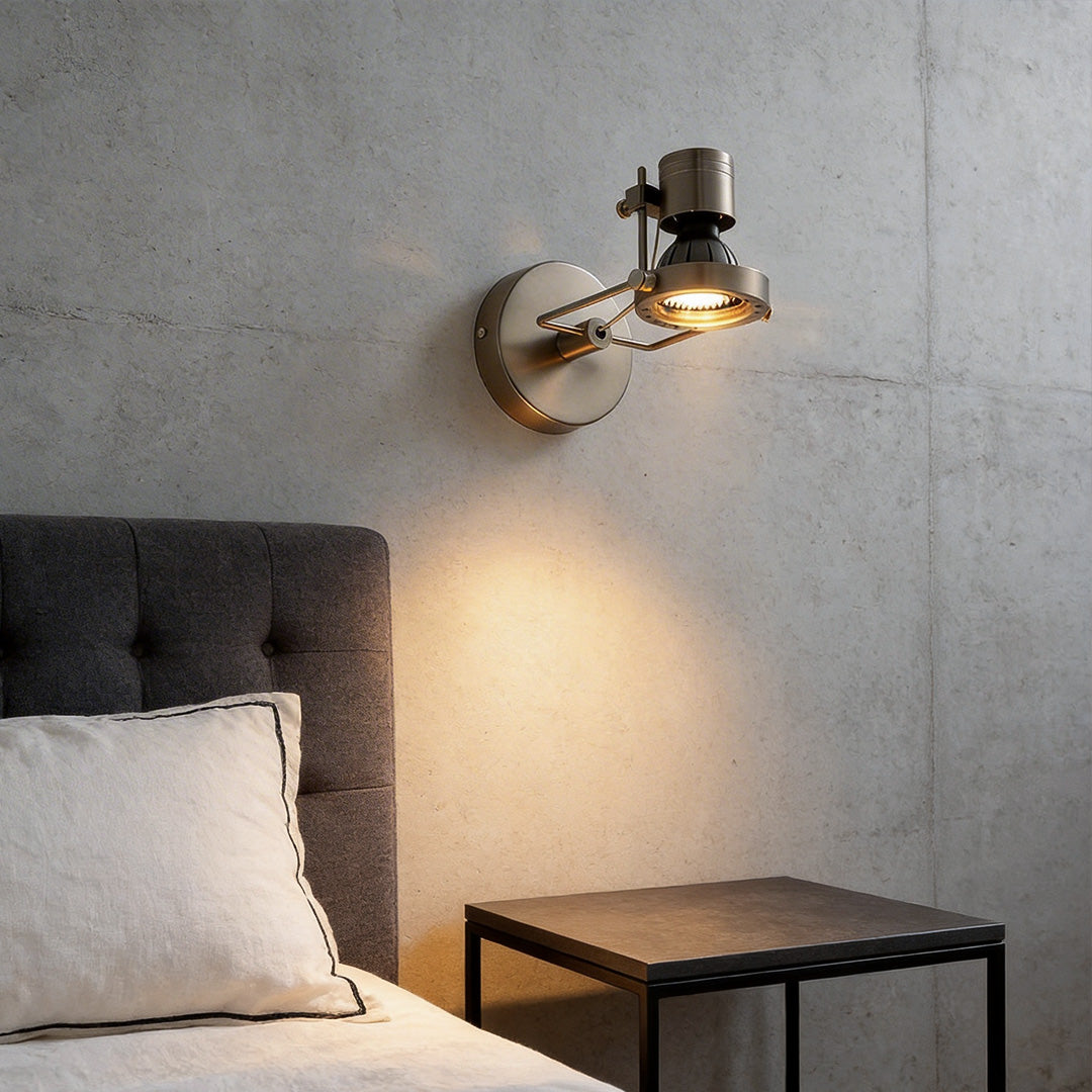 Industrial wall lights above a grey bed and black nightstand on a modern concrete textured wall.