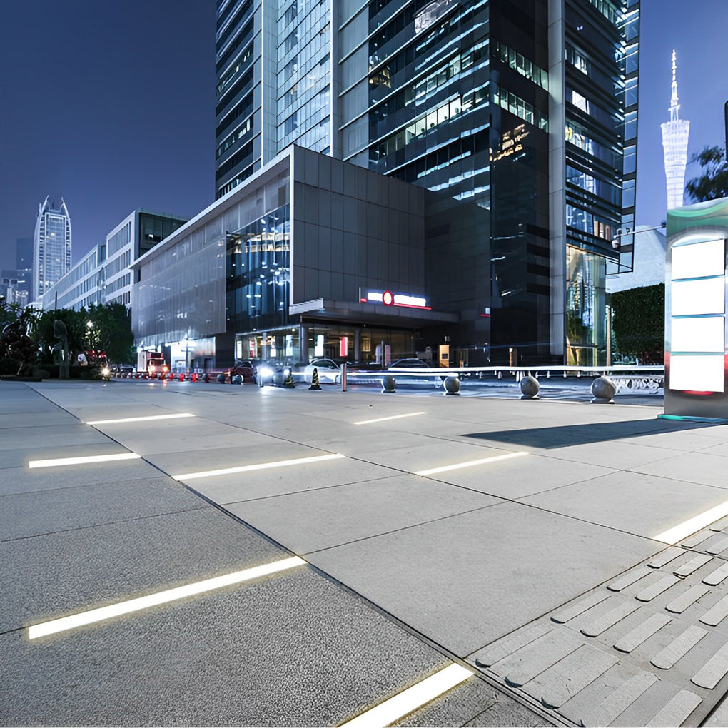 Inground linear lighting providing ambient light along a tree-lined pathway.