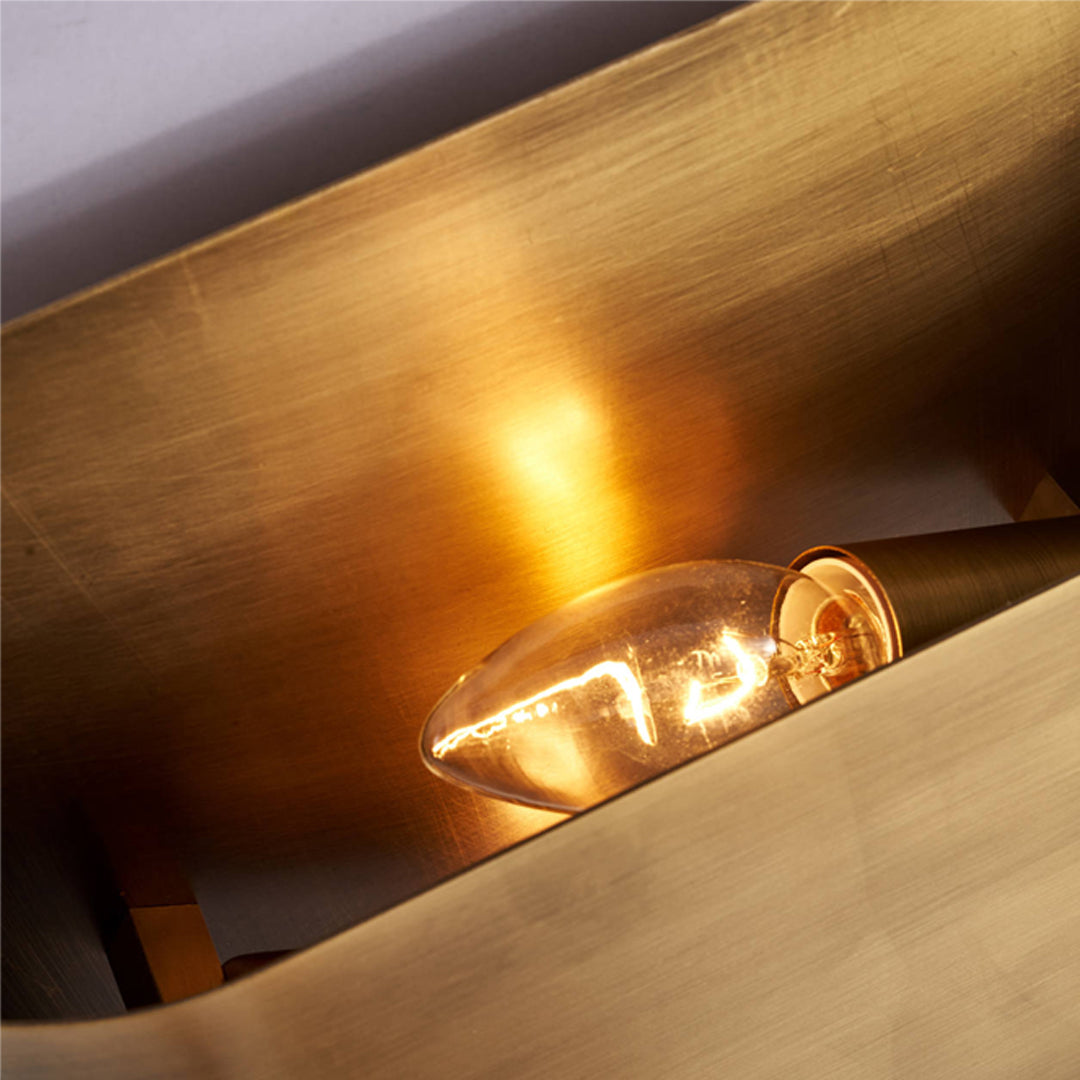 Inside view of a brass wall light showing a glowing vintage Edison bulb and metallic textures.