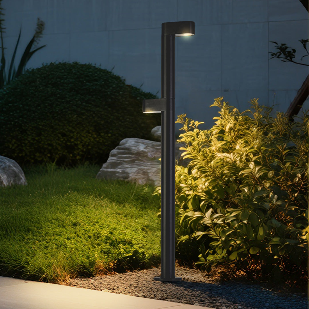 Black cylindrical LED path light bollard installed in outdoor setting showcasing modern landscape lighting