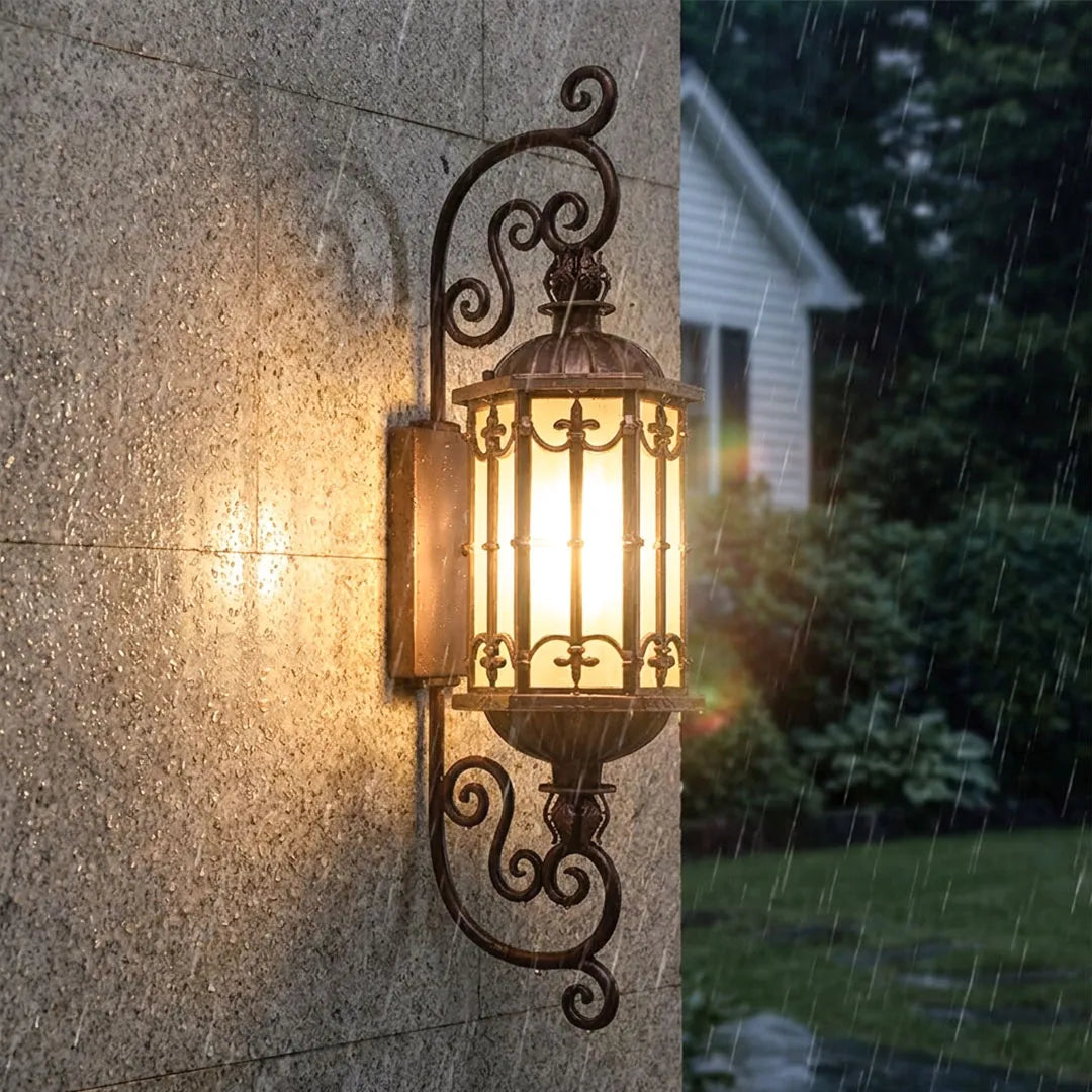 Vintage wall sconce lighting installed on an exterior wall with elegant bronze scroll details.