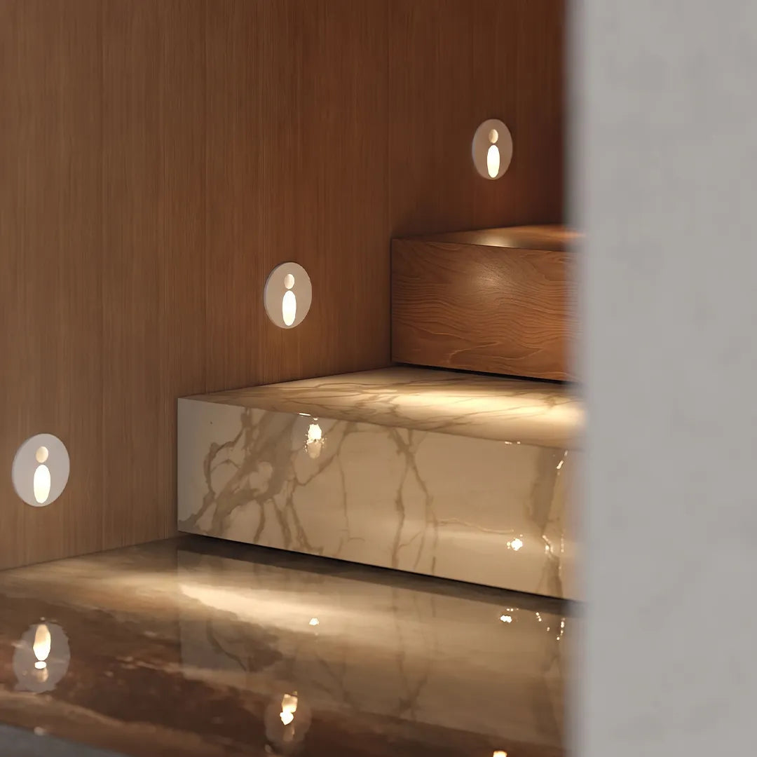 Interior stair step lights illuminating marble stairs and a wood-paneled wall with soft warm light.