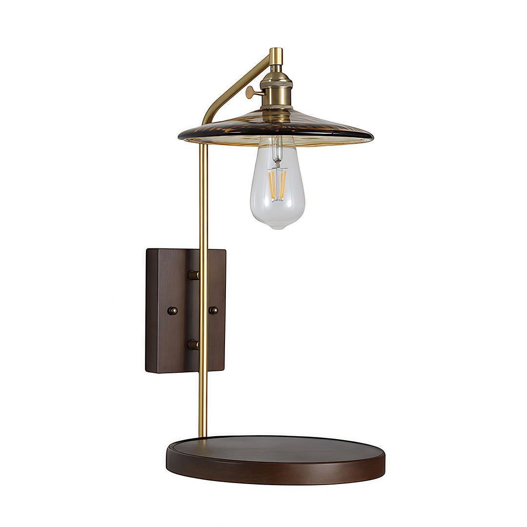 Isolated view of the glass wall lights fixture with a brass adjustable arm and a rustic wooden backplate and integrated shelf.