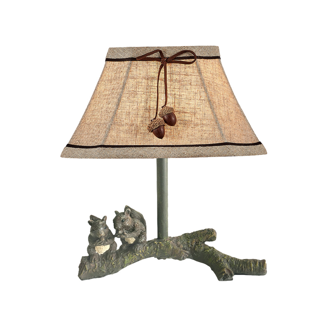 Isolated product view of the squirrel table lamp, highlighting the shade's natural fibers and the decorative acorn pull chains.