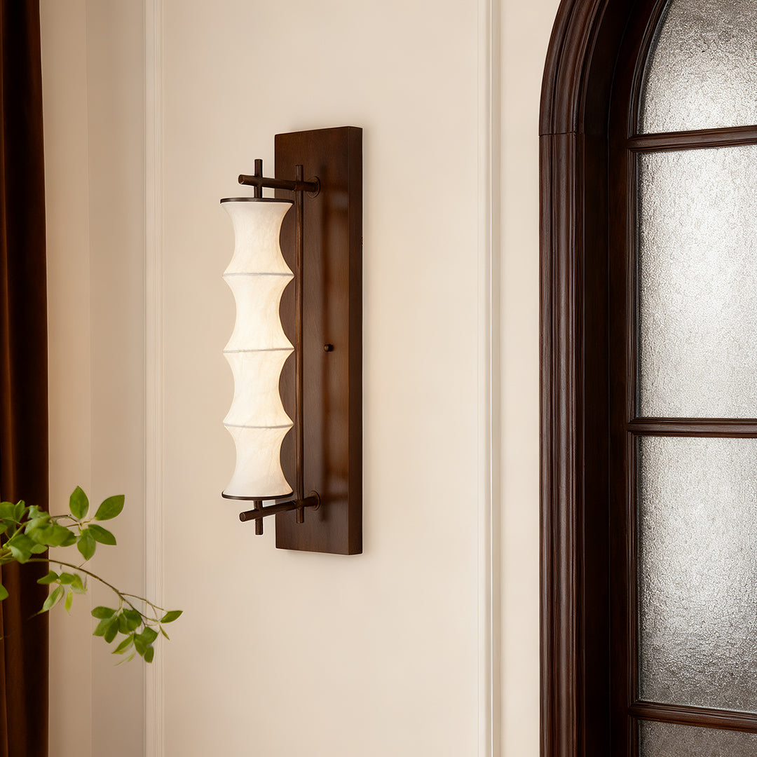 Isolated vintage light wall sconce, showing the tall, tiered fabric shade and dark walnut-finish backplate for a classic look.