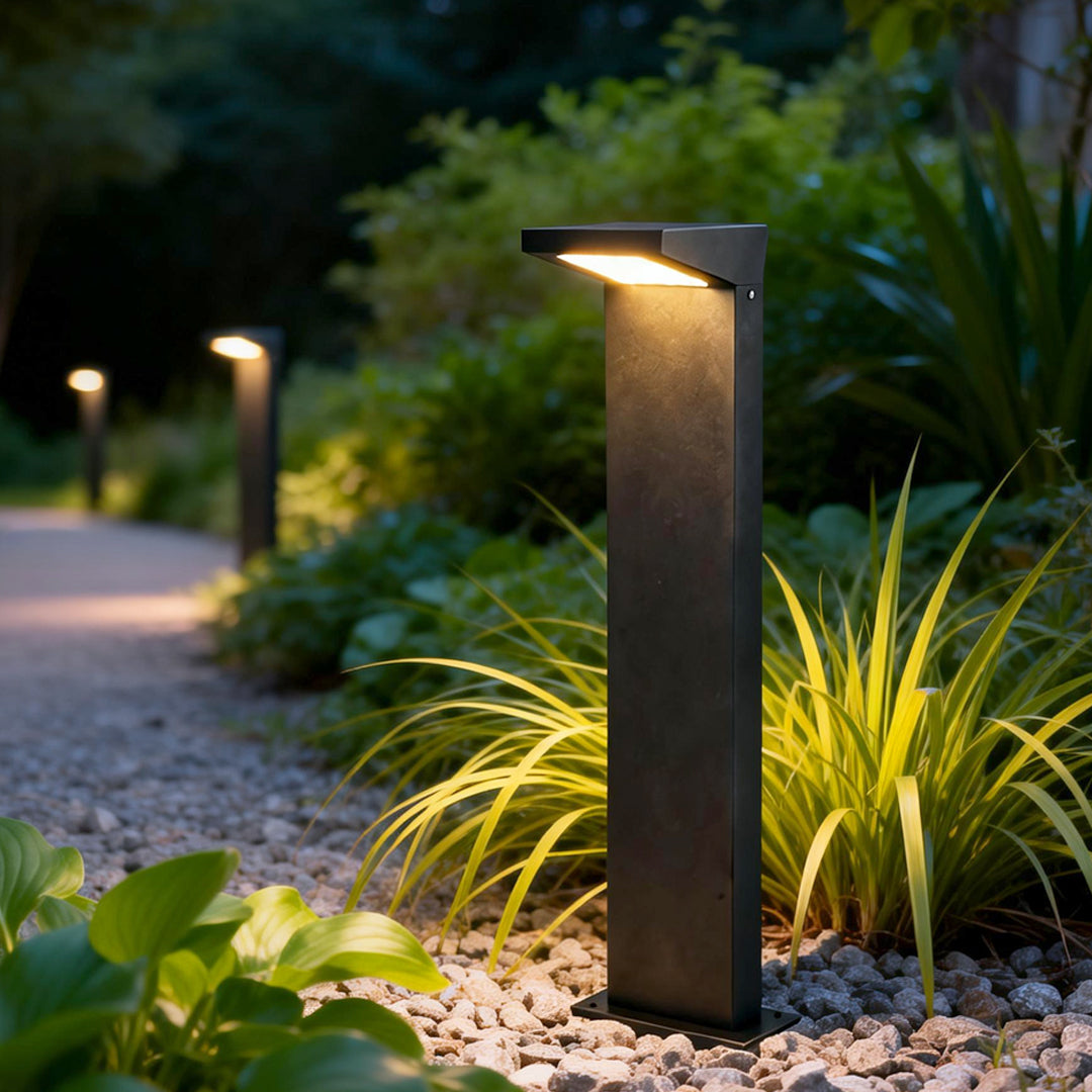 L bollard light illuminating a modern garden pathway with warm directional glow.