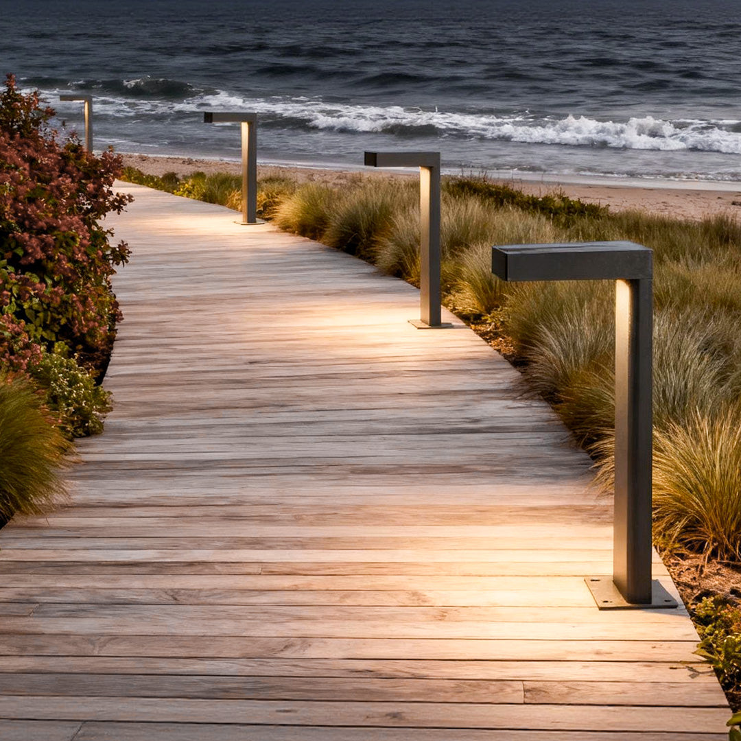 L shaped landscape light providing warm illumination along a wooden boardwalk near the beach.