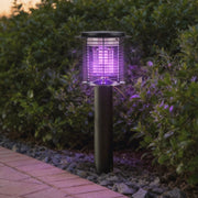 Lampara mata mosquitos with a sleek black design, providing purple UV light in a garden setting.