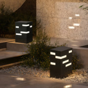 Outdoor black led bollard lights placed near a stone wall, creating a soft modern glow for accenting landscape features.