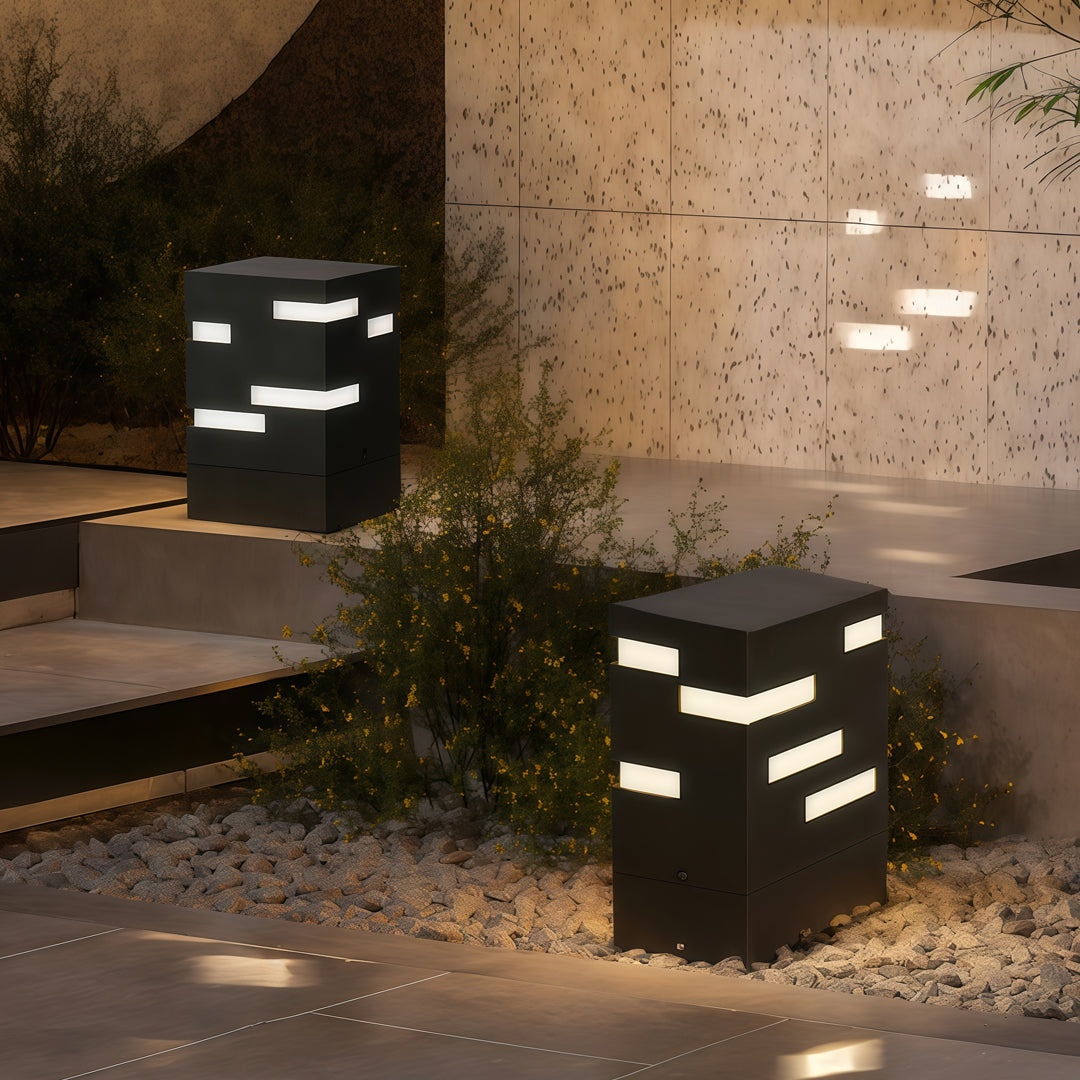 Outdoor black led bollard lights placed near a stone wall, creating a soft modern glow for accenting landscape features.