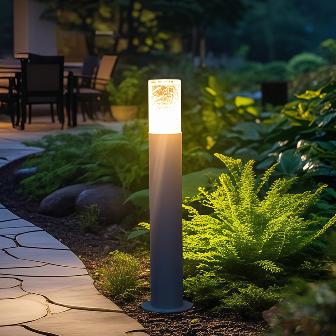 Bright landscape bollard light fixtures lining a backyard garden path, providing warm directional illumination.