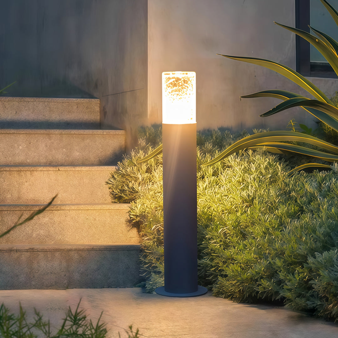 Landscape bollard light fixtures installed beside outdoor steps, casting warm pathway lighting at dusk.