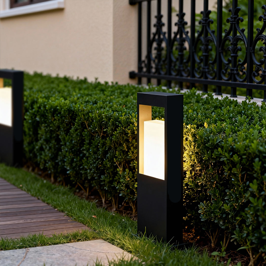 Modern landscape bollard lighting placed along hedges, offering warm ambient glow for outdoor paths.