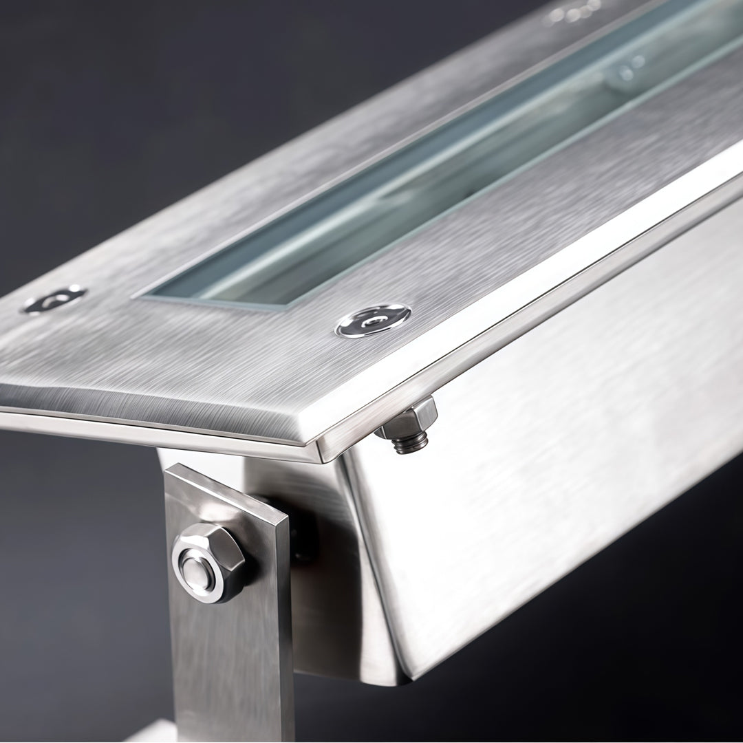 Close-up of landscape flood light showing brushed aluminum housing and mounting bracket detail.