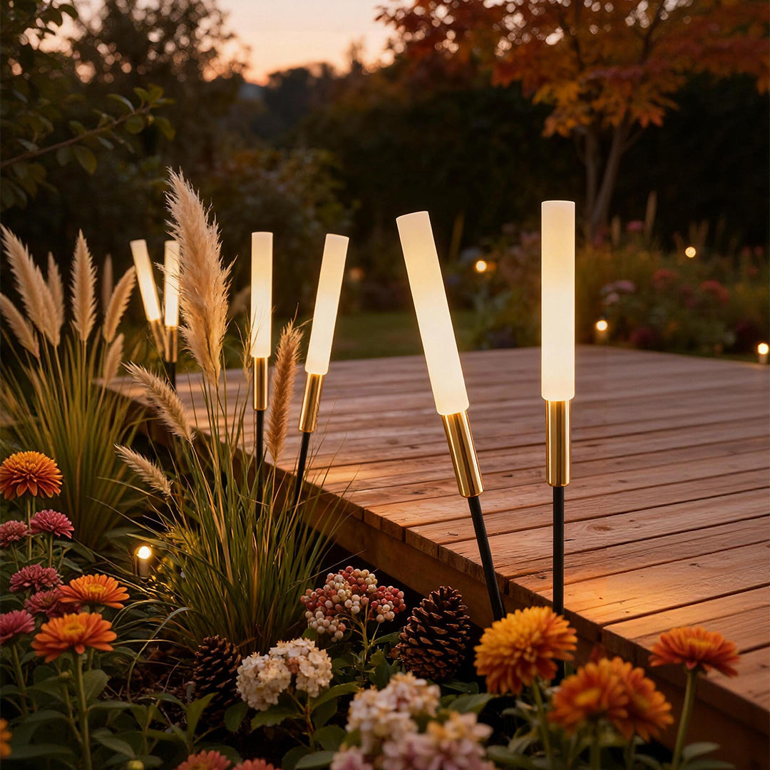 Landscape light spikes illuminating ornamental grasses along a wooden deck, creating a warm and inviting outdoor ambiance.