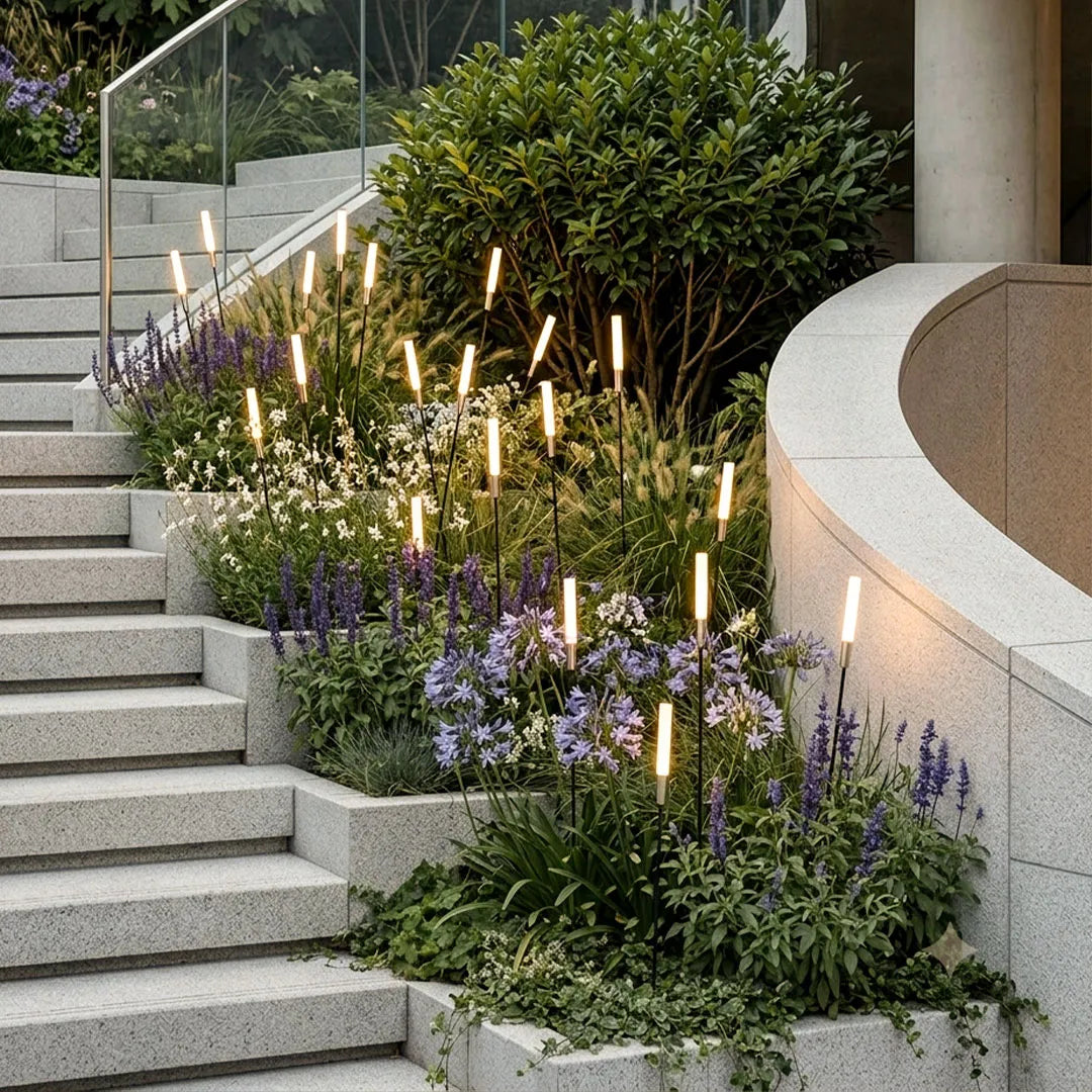 Landscape light spikes installed along stone garden steps with flowering plants and lush greenery.