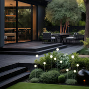 An outdoor deck and staircase bordered with glowing globe pathway lights, adding functional illumination to the landscape lighting pathway.