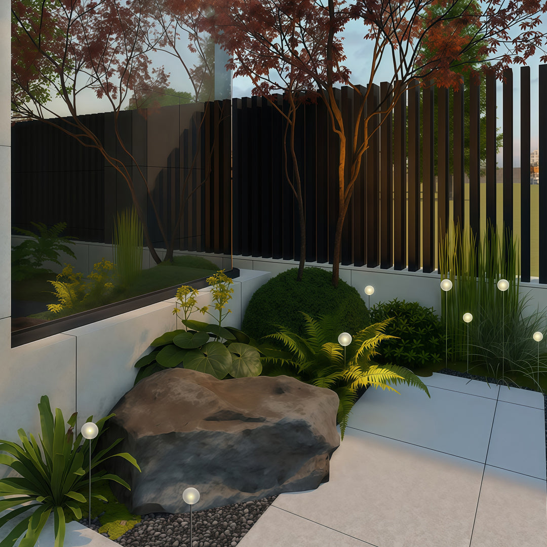 A lush landscaped area with decorative globe lights illuminating stones and plants, enhancing the outdoor space as landscape lighting pathway.
