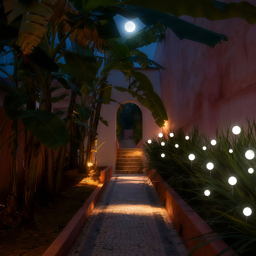 A narrow pathway lined with glowing globe garden lights, creating a warm guiding effect for landscape lighting pathway use.