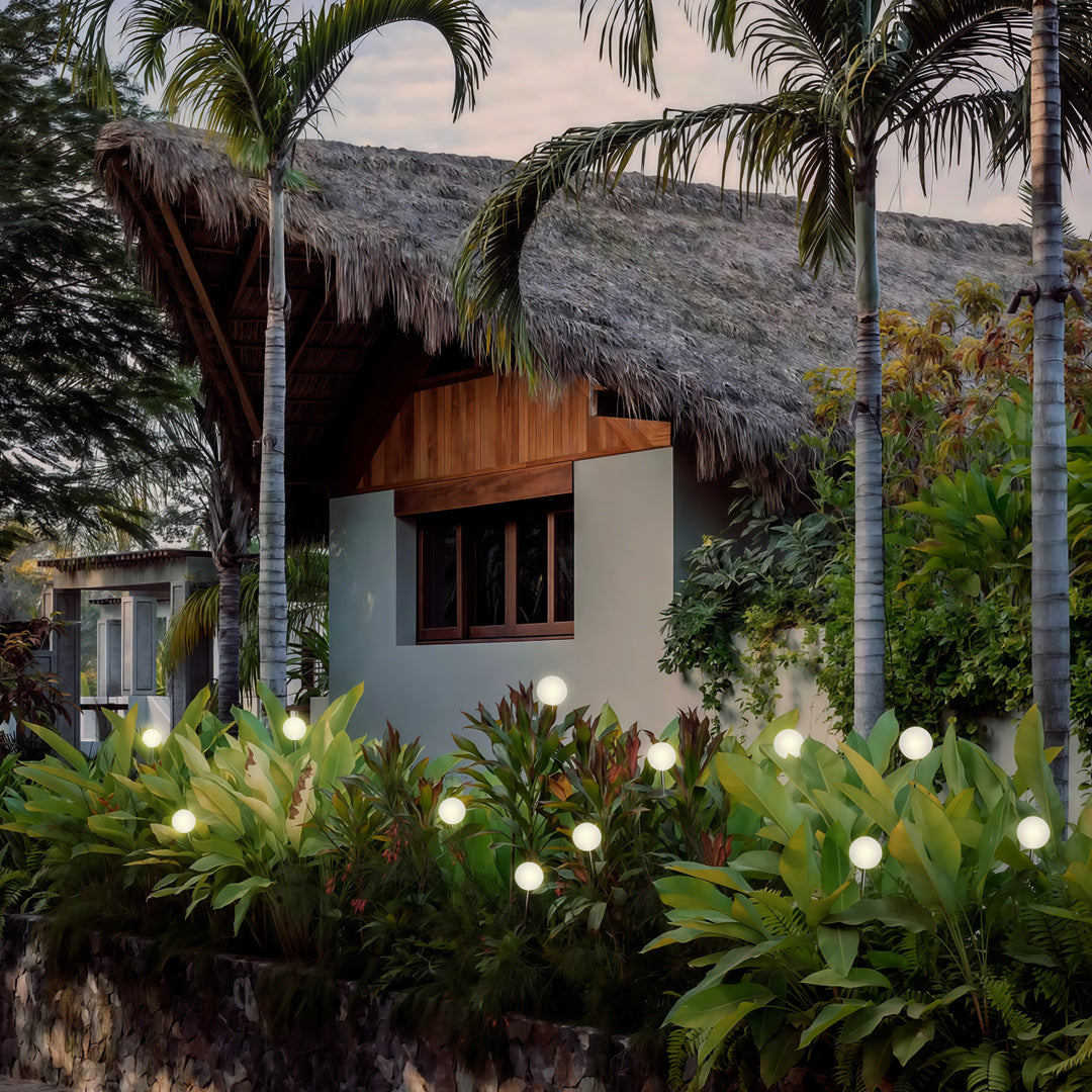 A natural garden setting illuminated with scattered globe pathway lights, creating warm, inviting landscape lighting pathway effects.