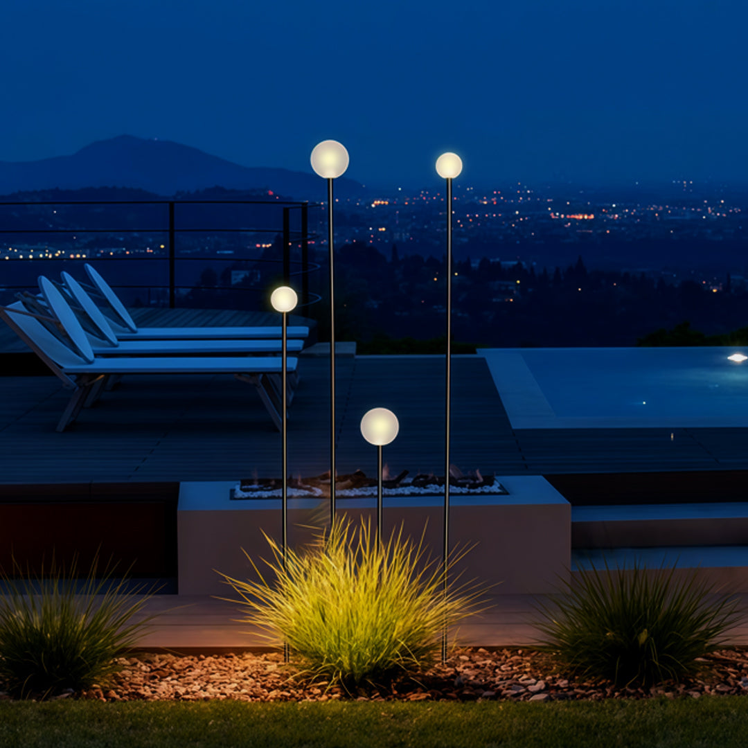 A nighttime garden scene featuring multiple glowing globe pathway lights placed along a terrace edge for landscape lighting pathway ambience.