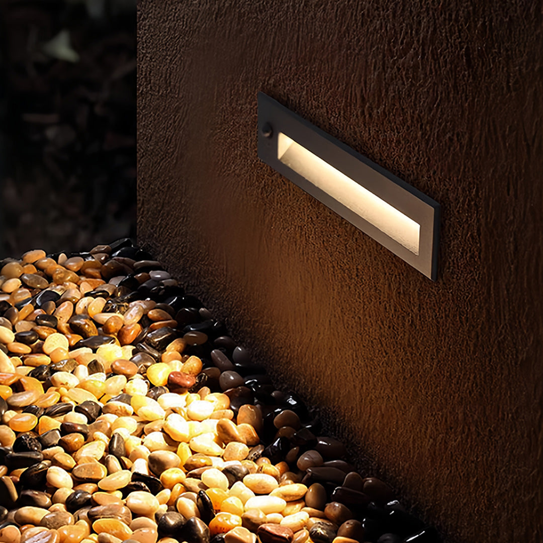 Deck lights for steps installed in landscape retaining wall creating warm pathway illumination