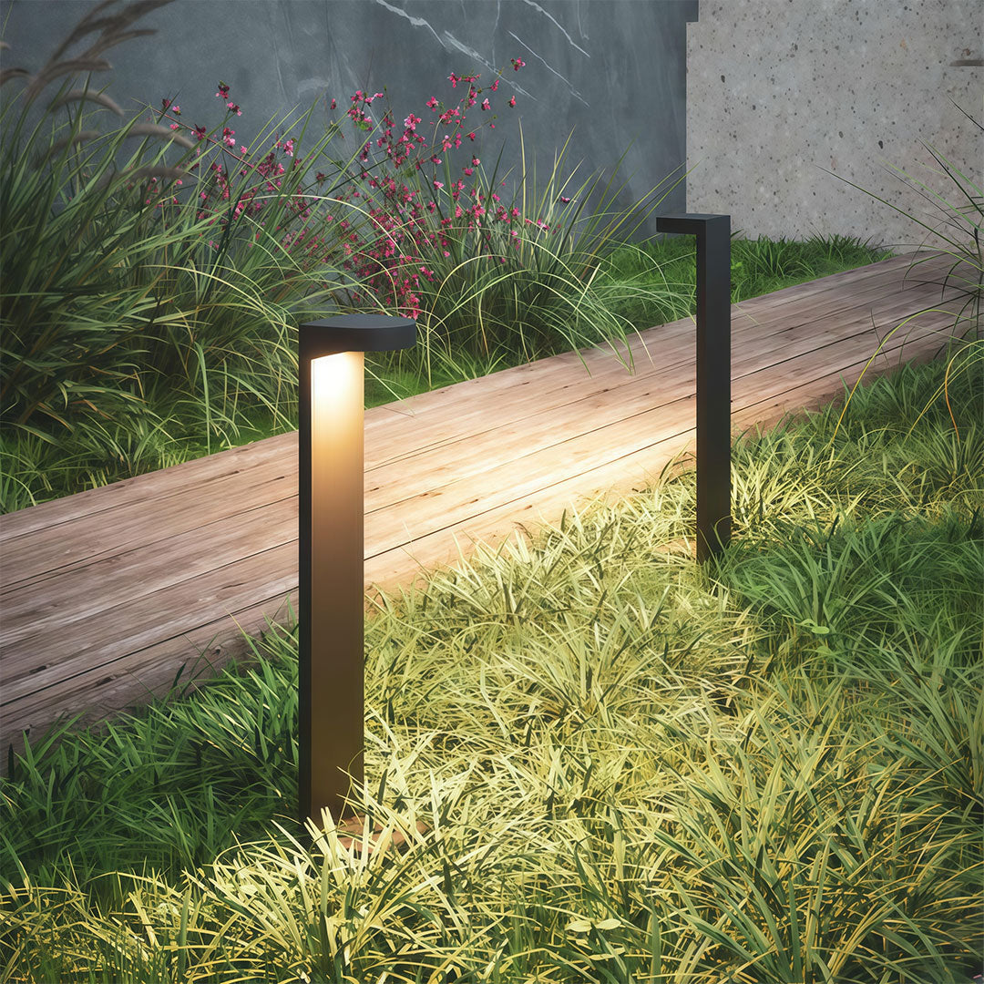 Landscape pathway light installed along a paved pathway, providing warm and inviting illumination.