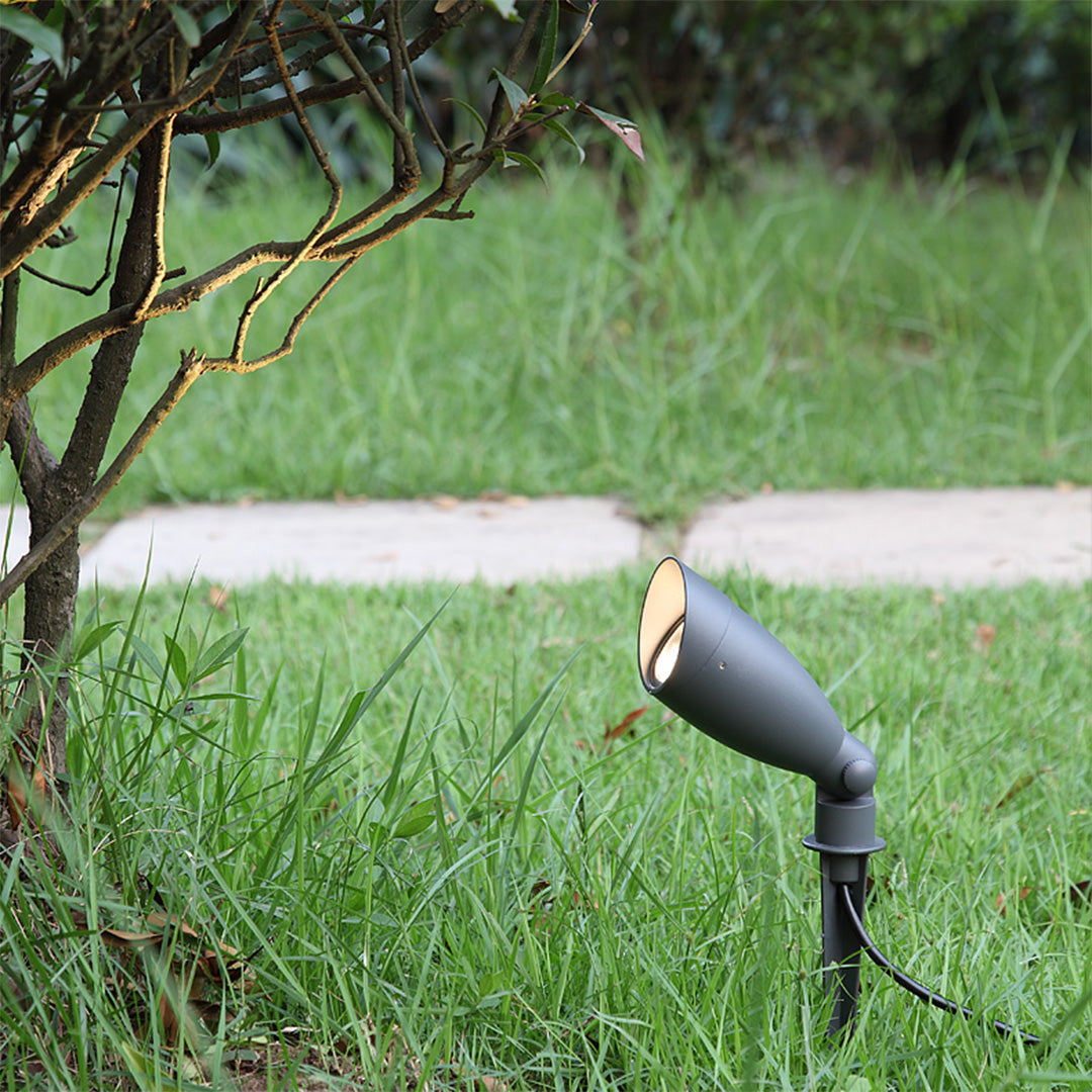 Landscape spotlight positioned in green lawn creating directional lighting for garden accent illumination