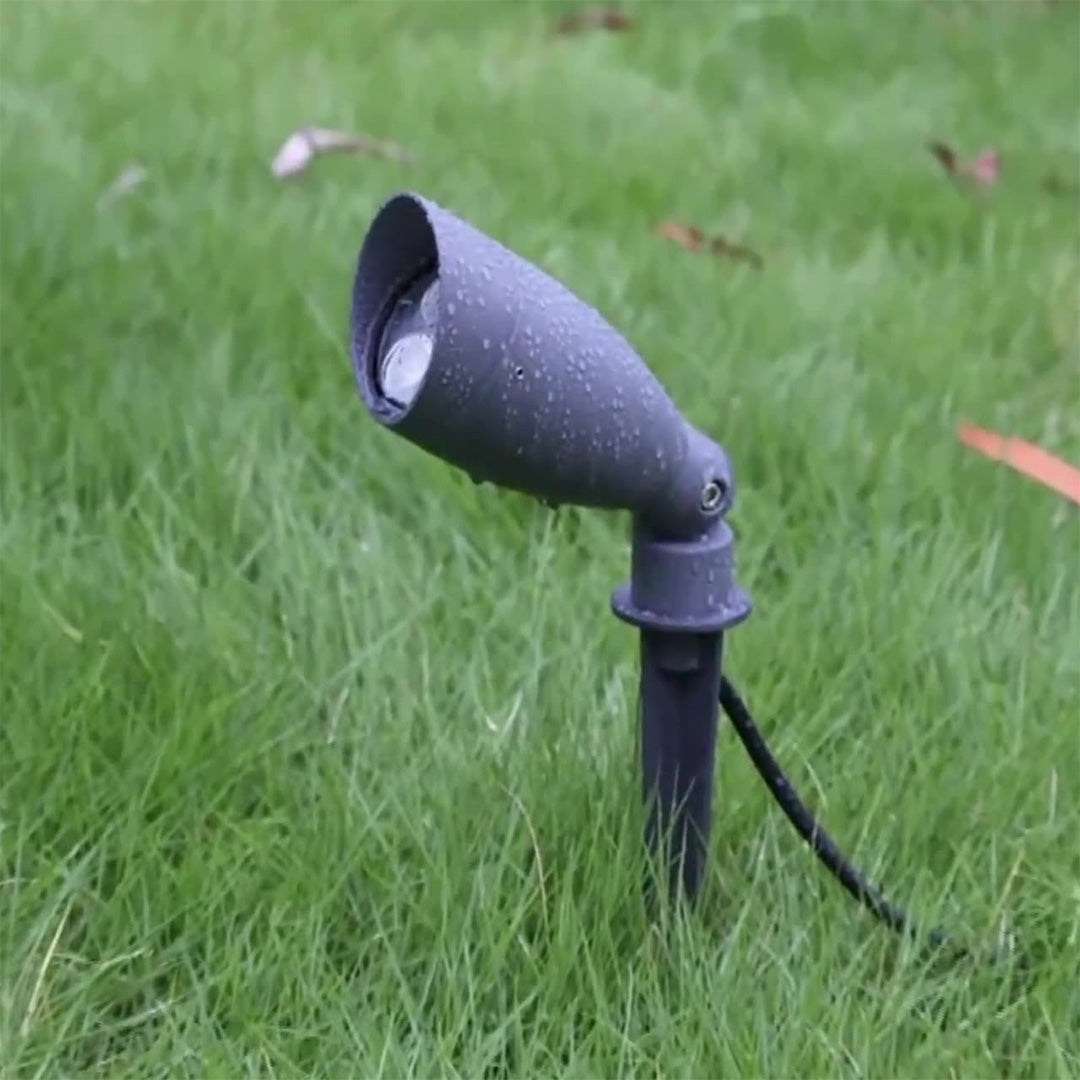 Landscape spotlight positioned in green lawn creating directional lighting for garden accent illumination