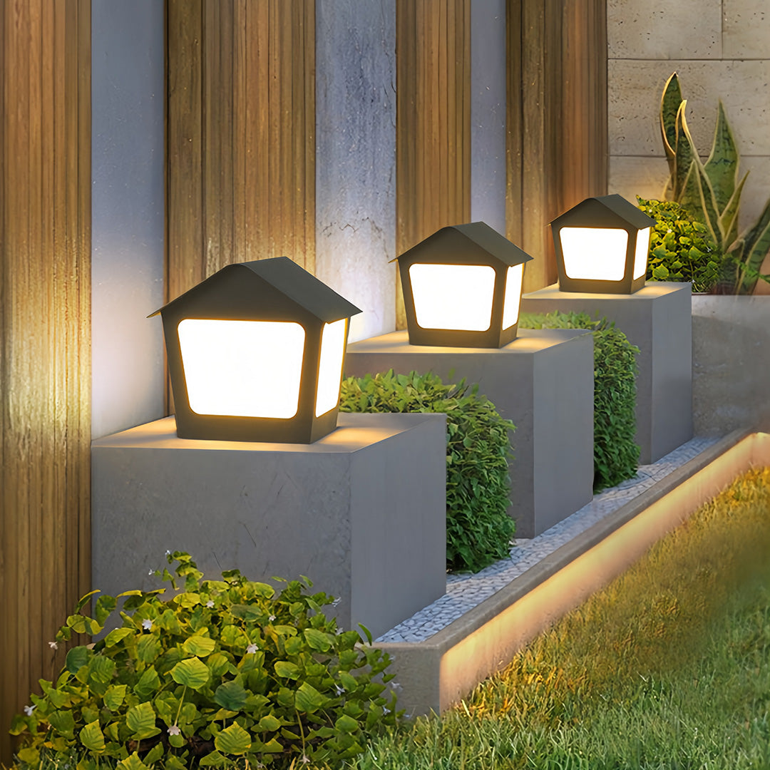 Outdoor landscape lighting featuring multiple deck post cap lights set on tiered garden borders and textured walls.