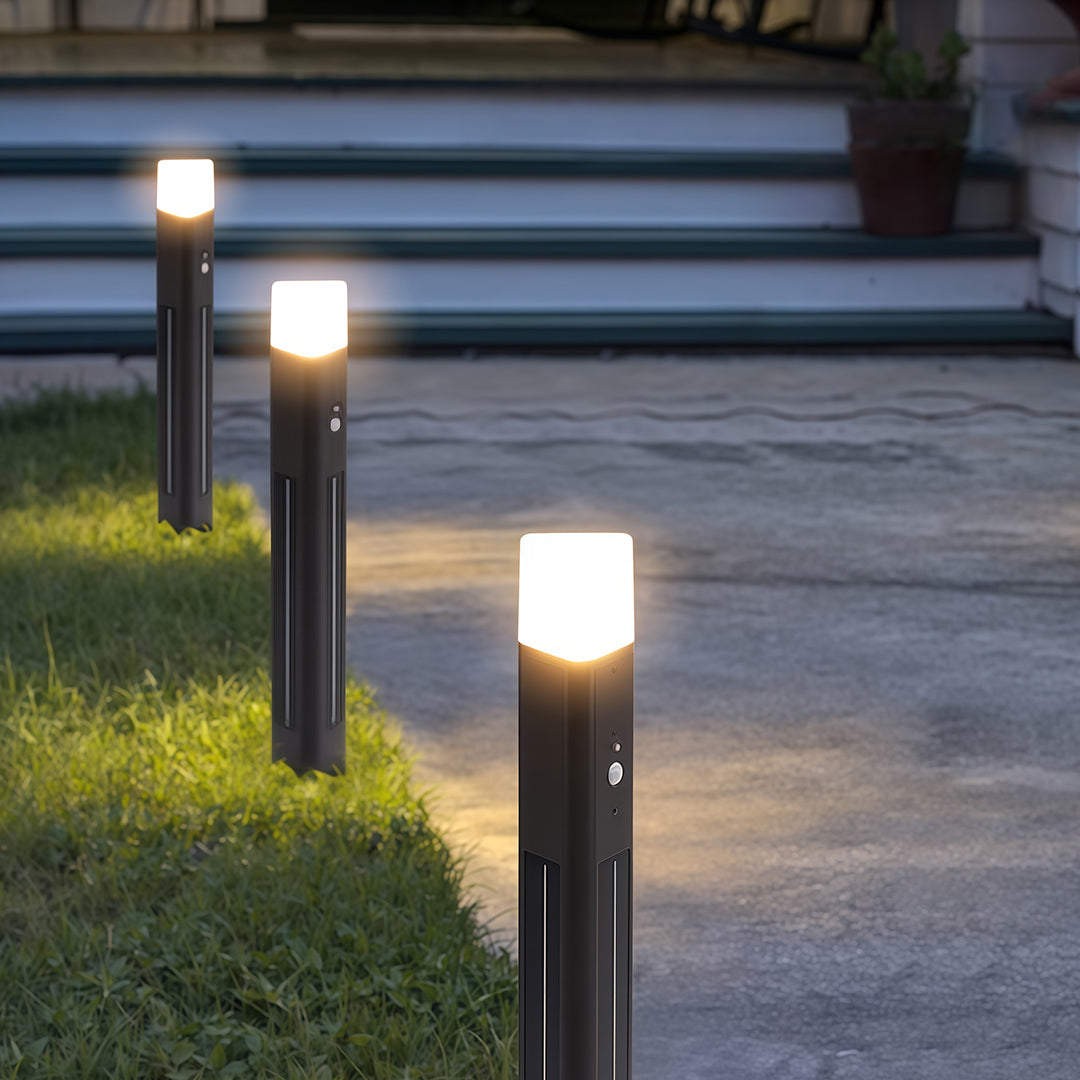 Black solar bollard lighting along a landscaped pathway, offering energy-efficient illumination.