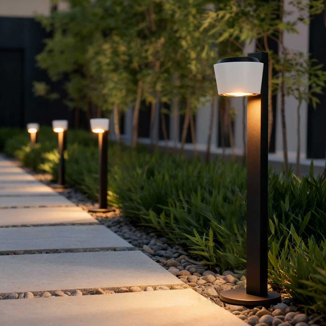 Contemporary garden lights path fixture lighting a landscaped walkway surrounded by greenery.