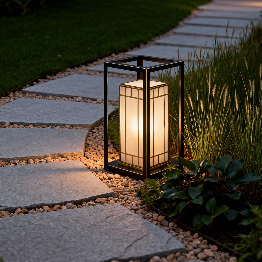 Lantern bollard light lining a paved path with greenery, offering decorative and practical lighting for outdoor pathways.