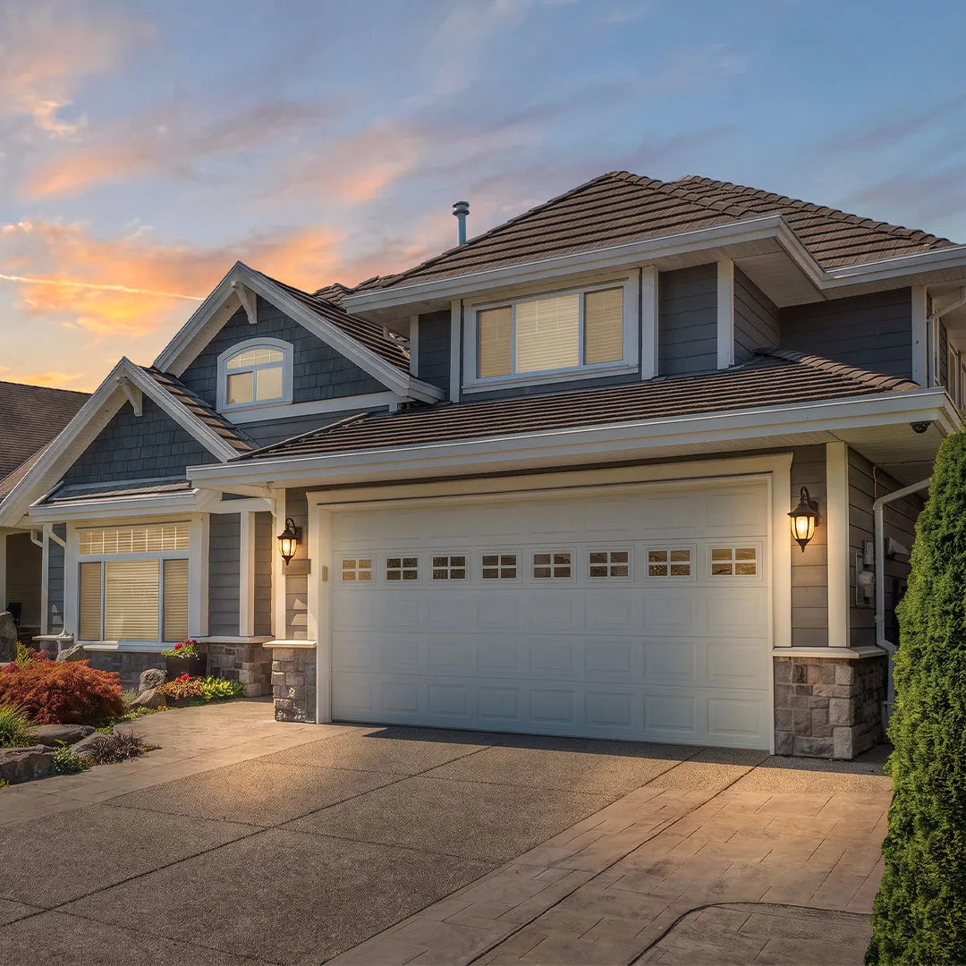 Lantern outdoor wall lights illuminating a residential garage and driveway at dusk.