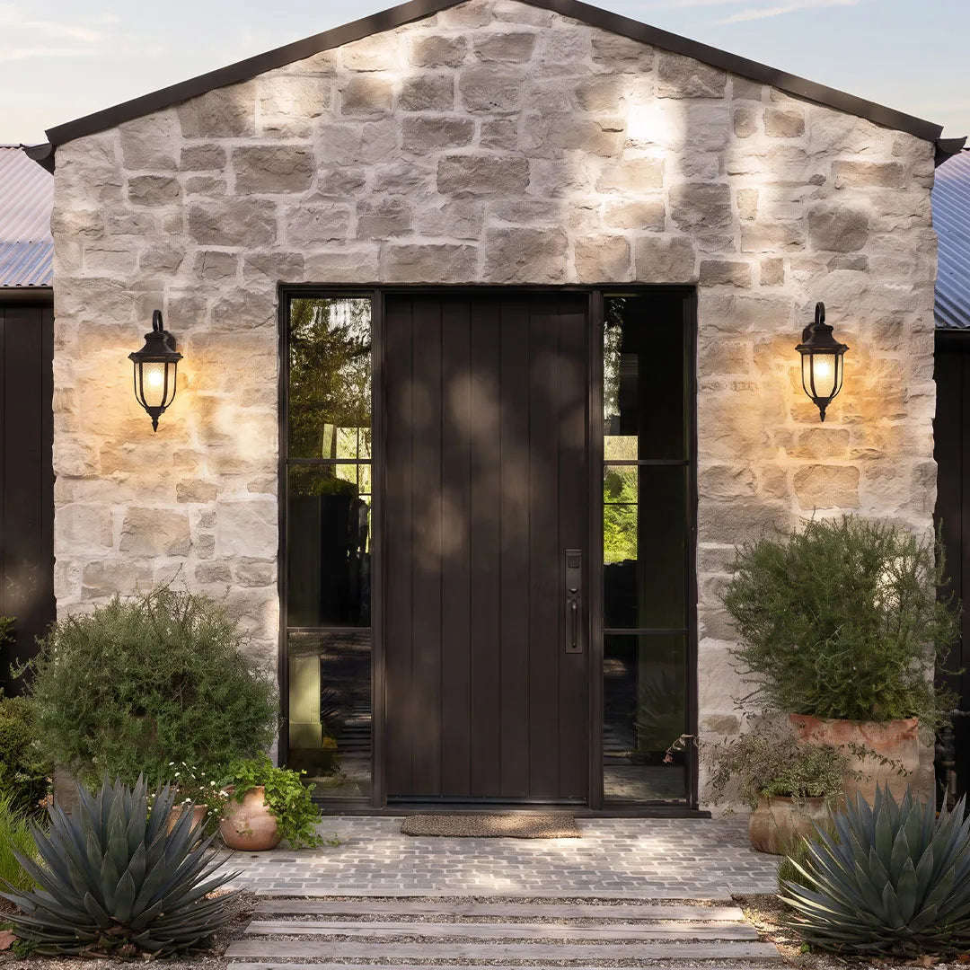 Lantern outdoor wall lights installed beside a modern stone home entrance for welcoming exterior illumination.