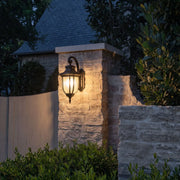 Lantern outdoor wall lights mounted on a stone entrance pillar for warm nighttime landscape lighting.