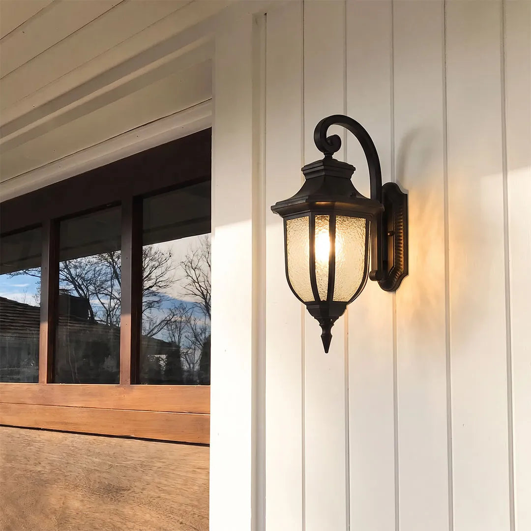 Lantern outdoor wall lights mounted on white siding with seeded glass and a traditional black frame.