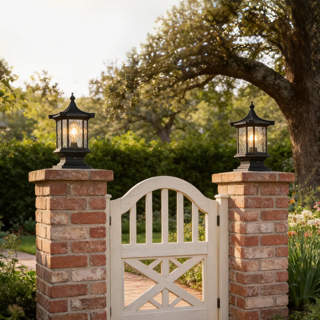 Lantern pillar lights decorating brick gate posts with a white garden gate entrance.