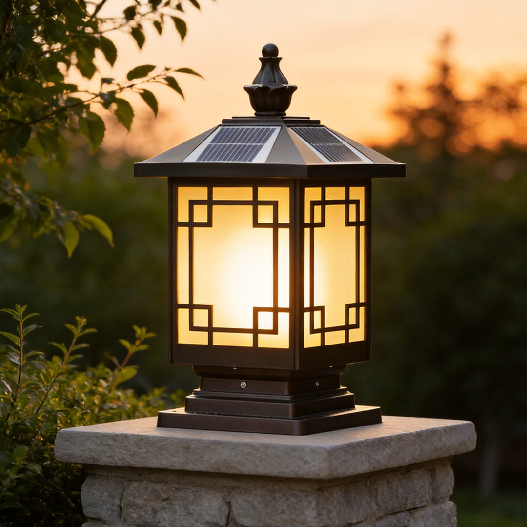 Lantern pillar lights glowing warmly on a garden post with sunset background and greenery.