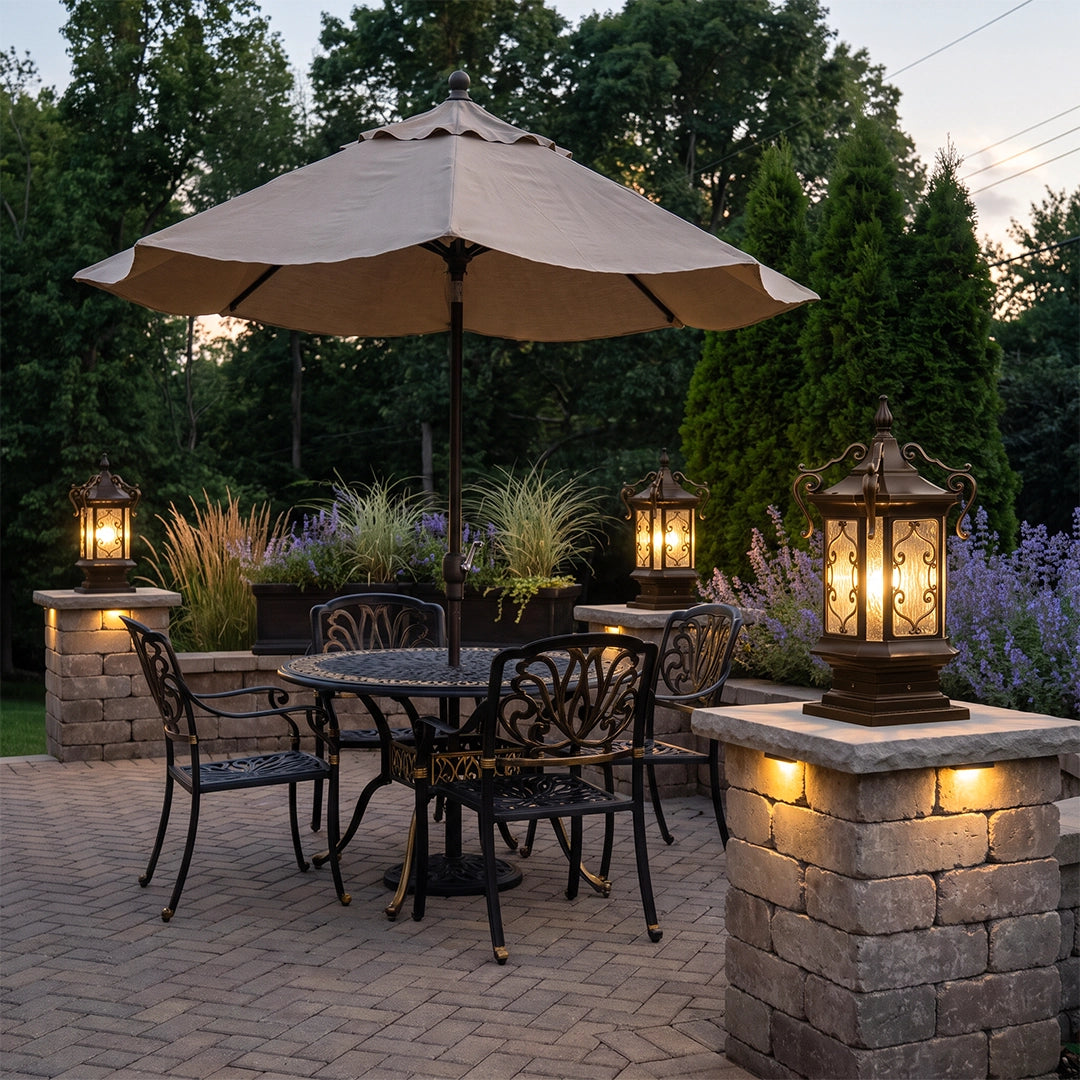 Lantern pillar lights styled on an outdoor patio wall and stone column beside a dining table and umbrella.